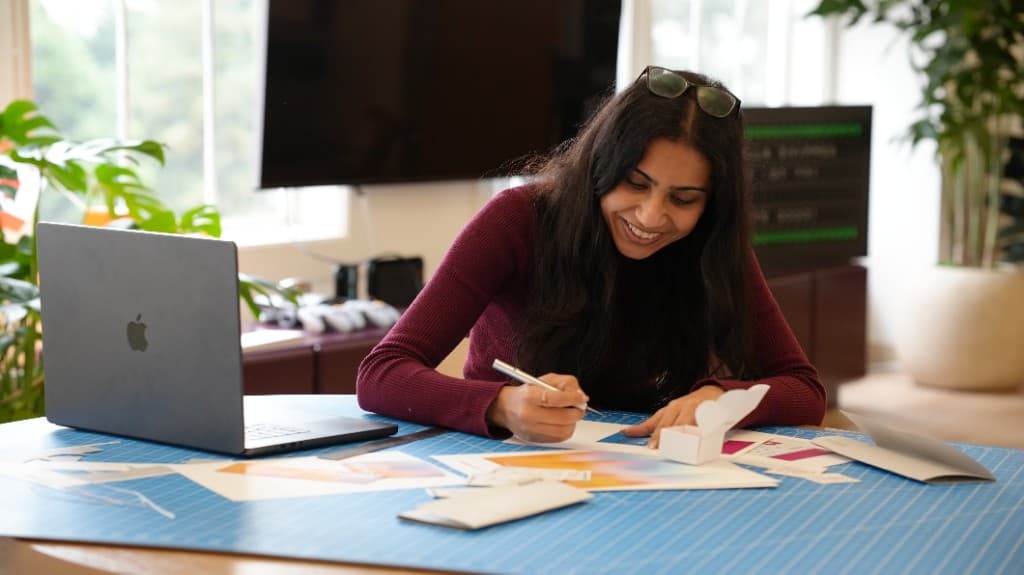 A Gumlooper smiling while sketching designs at the office table